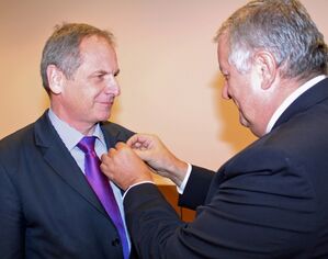 Der ungarische Botschafter Jozsef Czukor steckt Reinhold Gall das Ehrungszeichen an